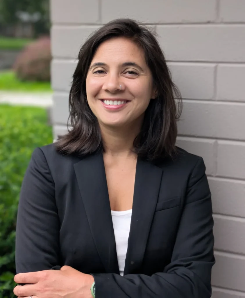 This is a picture of Anjuli, the CEO of Anjuli Consulting. She has brown hair, brown eyes, and tan skin.